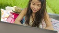 Young beautiful and happy Asian Korean woman working outdoors with laptop computer networking green grass background cafe as digit Royalty Free Stock Photo