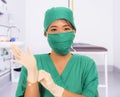 Young beautiful and happy Asian medicine doctor or chief hospital nurse in green scrubs and surgey hat and mask putting  latex Royalty Free Stock Photo