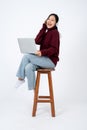 Young happy Asian woman enjoys listening to music through headphones while sitting on a chair Royalty Free Stock Photo