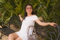 Young beautiful and happy Asian woman on park bench - lifestyle portrait of Attractive Chinese girl in Summer dress resting during Royalty Free Stock Photo