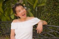 Young beautiful and happy Asian woman on park bench - lifestyle portrait of Attractive Japanese girl in Summer dress resting Royalty Free Stock Photo