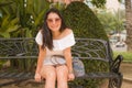 Young beautiful and happy Asian woman on park bench - lifestyle portrait of Attractive Korean girl in Summer dress resting during Royalty Free Stock Photo