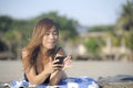Beautiful and happy Asian woman using mobile phone texting on internet social media smiling relaxed Royalty Free Stock Photo