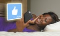 Young beautiful and happy black African American woman using mobile phone social media smiling cheerful lying on bed at home Royalty Free Stock Photo