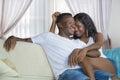 Young beautiful happy black afro American couple in love relaxed at modern home living room cuddling sweet on sofa couch smiling Royalty Free Stock Photo