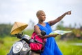 Young beautiful and happy black afro american tourist woman with scooter motorbike looking to road map searching destination explo Royalty Free Stock Photo