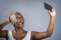 Young beautiful and happy black afro American woman excited taking selfie picture showing proud her shaved head hair style Royalty Free Stock Photo