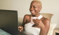 Young beautiful and happy black afro American woman smiling excited having fun on internet using social media on laptop computer Royalty Free Stock Photo