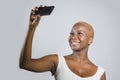 Young beautiful and happy black afro American woman smiling excited taking selfie picture portrait with mobile phone or recording Royalty Free Stock Photo