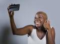 Young beautiful and happy black afro American woman smiling excited taking selfie picture portrait with mobile phone or recording Royalty Free Stock Photo