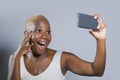 Young beautiful and happy black afro American woman smiling excited taking selfie picture portrait with mobile phone or recording Royalty Free Stock Photo