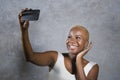 Young beautiful and happy black afro American woman smiling excited taking selfie picture portrait with mobile phone or recording Royalty Free Stock Photo