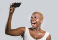 Young beautiful and happy black afro American woman smiling excited taking selfie picture portrait with mobile phone or recording Royalty Free Stock Photo