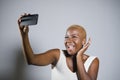 Young beautiful and happy black afro American woman smiling excited taking selfie picture portrait with mobile phone or recording Royalty Free Stock Photo