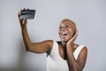 Young beautiful and happy black afro American woman smiling excited taking selfie picture portrait with mobile phone or recording Royalty Free Stock Photo