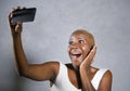 Young beautiful and happy black afro American woman smiling excited taking selfie picture portrait with mobile phone or recording Royalty Free Stock Photo