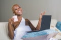 Young beautiful happy black afro American woman smiling working on laptop computer at home relaxed on sofa couch in internet onlin Royalty Free Stock Photo