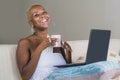 Young beautiful happy black afro American woman smiling working on laptop computer at home relaxed on sofa couch in internet onlin Royalty Free Stock Photo