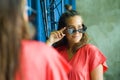 Young beautiful and happy blond woman enjoying shopping trying out clothes and sunglasses in the mirror at vintage and cool beauty Royalty Free Stock Photo