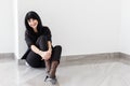 Young Beautiful happy brunette woman dressed in a black business suit sitting on a floor in office, smiling, looking at camera Royalty Free Stock Photo