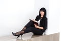 Young Beautiful happy brunette woman holding a notebook dressed in a black business suit sitting on a floor in a office, smiling, Royalty Free Stock Photo