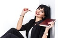 Young Beautiful happy brunette woman holding a notebook dressed in a black business suit sitting on a floor in a office, smiling, Royalty Free Stock Photo