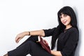 Young Beautiful happy brunette woman holding a notebook dressed in a black business suit sitting on a floor in a office, smiling, Royalty Free Stock Photo