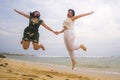 Young beautiful and happy couple of attractive Asian Korean women jumping on the air together at the beach enjoying holidays Royalty Free Stock Photo