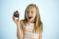 Young beautiful happy and excited blond girl 8 or 9 years old holding chocolate cake on her hand looking spastic and cheerful in s Royalty Free Stock Photo