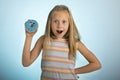 Young beautiful happy and excited blond girl 8 or 9 years old holding donut desert on her hand looking spastic and cheerful in sug