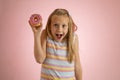 Young beautiful happy and excited blond girl 8 or 9 years old holding donut desert on her hand looking spastic and cheerful in sug