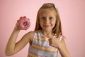 Young beautiful happy and excited blond girl 8 or 9 years old holding donut desert on her hand looking spastic and cheerful in sug