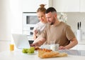 Young beautiful happy family couple reading news on laptop during morning breakfast at home Royalty Free Stock Photo