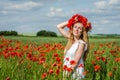 Young beautiful happy girl with long hair in a white dress in the poppy field with a wreath on his head Royalty Free Stock Photo