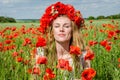 Young beautiful happy girl with long hair in a white dress in the poppy field with a wreath on his head Royalty Free Stock Photo