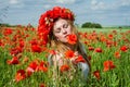 Young beautiful happy girl with long hair in a white dress in the poppy field with a wreath on his head Royalty Free Stock Photo