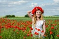 Young beautiful happy girl with long hair in a white dress in the poppy field with a wreath on his head Royalty Free Stock Photo