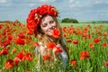 Young beautiful happy girl with long hair in a white dress in the poppy field with a wreath on his head Royalty Free Stock Photo