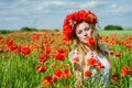 Young beautiful happy girl with long hair in a white dress in the poppy field with a wreath on his head Royalty Free Stock Photo