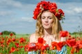 Young beautiful happy girl with long hair in a white dress in the poppy field with a wreath on his head Royalty Free Stock Photo