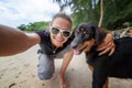 Young beautiful happy joyful girl woman having fun taking a selfie on a mobile phone with her dog on the beach along the sand Royalty Free Stock Photo