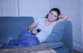 Young beautiful and happy latin woman on her 30s holding TV remote enjoying at home living room couch watching television show Royalty Free Stock Photo