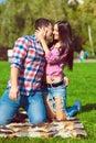 Young beautiful happy loving couple in checked shirts and jeans standing on their knees on the green lawn and kissing Royalty Free Stock Photo