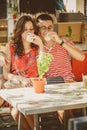 Young beautiful happy loving couple sitting at street open-air cafe, hugging, drinking yoghurt or milk. Food, lifestyle concept.