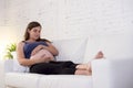 Young beautiful happy 8 or 9 months pregnant woman at home living room couch holding big belly Royalty Free Stock Photo