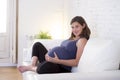 Young beautiful happy 8 or 9 months pregnant woman at home living room couch holding big belly Royalty Free Stock Photo