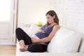 Young beautiful happy 8 or 9 months pregnant woman at home living room couch holding big belly Royalty Free Stock Photo