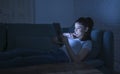 Young beautiful happy and relaxed latin woman 30s lying on home couch late night using digital device laptop tablet pad watching Royalty Free Stock Photo