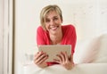 Young beautiful happy 30s woman smiling using digital tablet pad at home living room couch Royalty Free Stock Photo