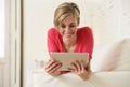 Young beautiful happy 30s woman smiling using digital tablet pad at home living room couch Royalty Free Stock Photo